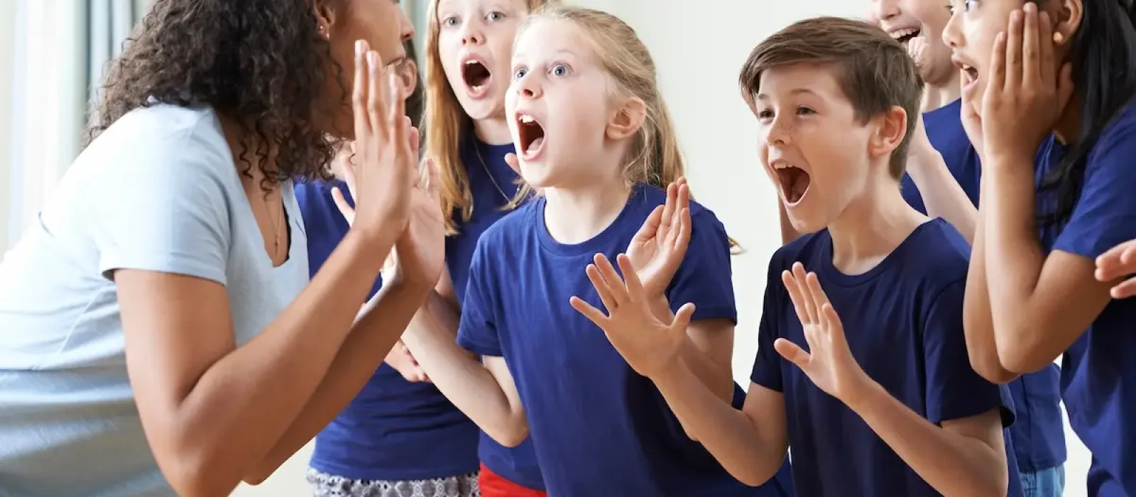 Group Of Children With Teacher Enjoying Drama Class Together