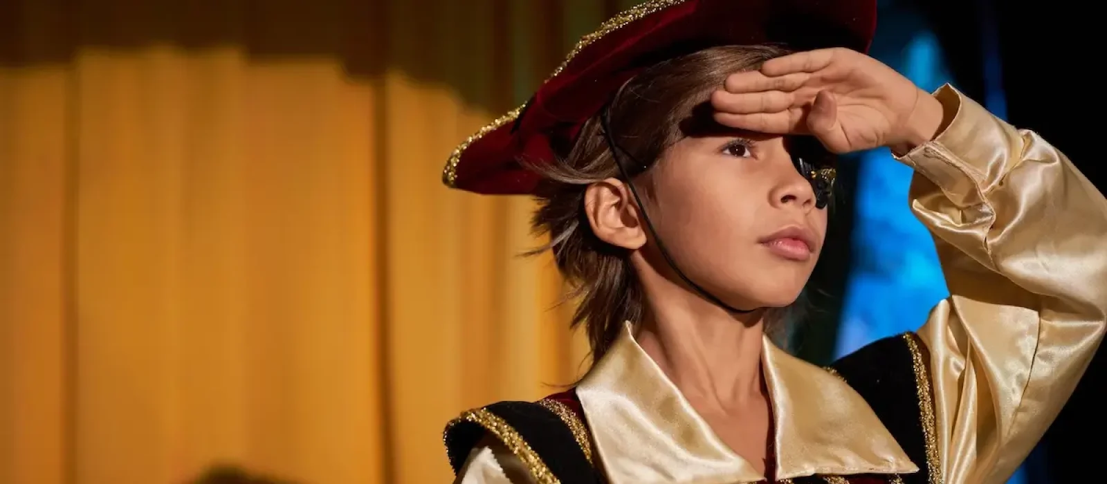 Boy performing on stage in spotlight Waist up portrait of boy wearing pirate costume performing on stage in spotlight and talking to audience, copy space